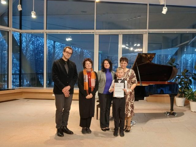 laureāts kopā ar skolotāju O. Mauerzaku un zūrijas locekļiem pie klavierēm