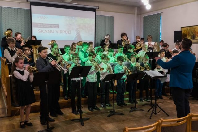 skats uz bērnu un jauniešu orķestri, priekšā diriģents