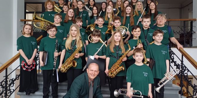 kopbildē - mūsu pūtēju orķestris kopā ar diriģentu - uz kapnēm, turot rokās savus instrumentus.